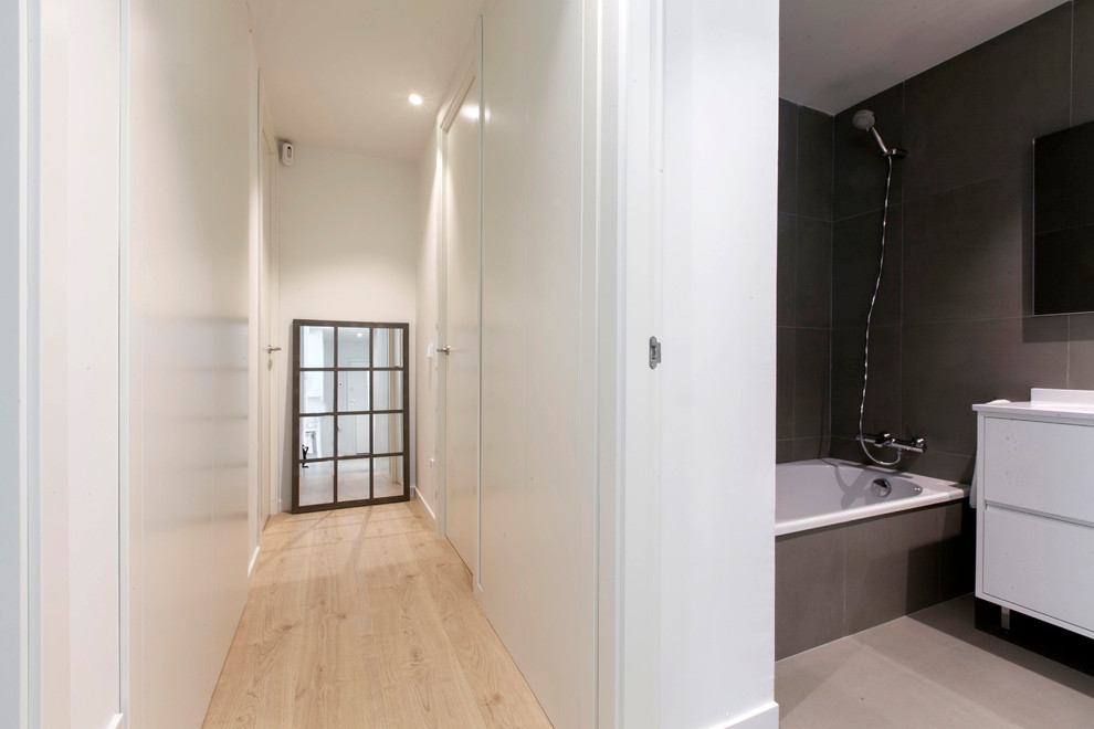 Imagen de aseo escandinavo pequeño con armarios con paneles lisos, sanitario de pared, baldosas y/o azulejos grises, baldosas y/o azulejos de porcelana, paredes grises, suelo de baldosas de porcelana, lavabo bajoencimera, encimera de cuarzo compacto y puertas de armario blancas