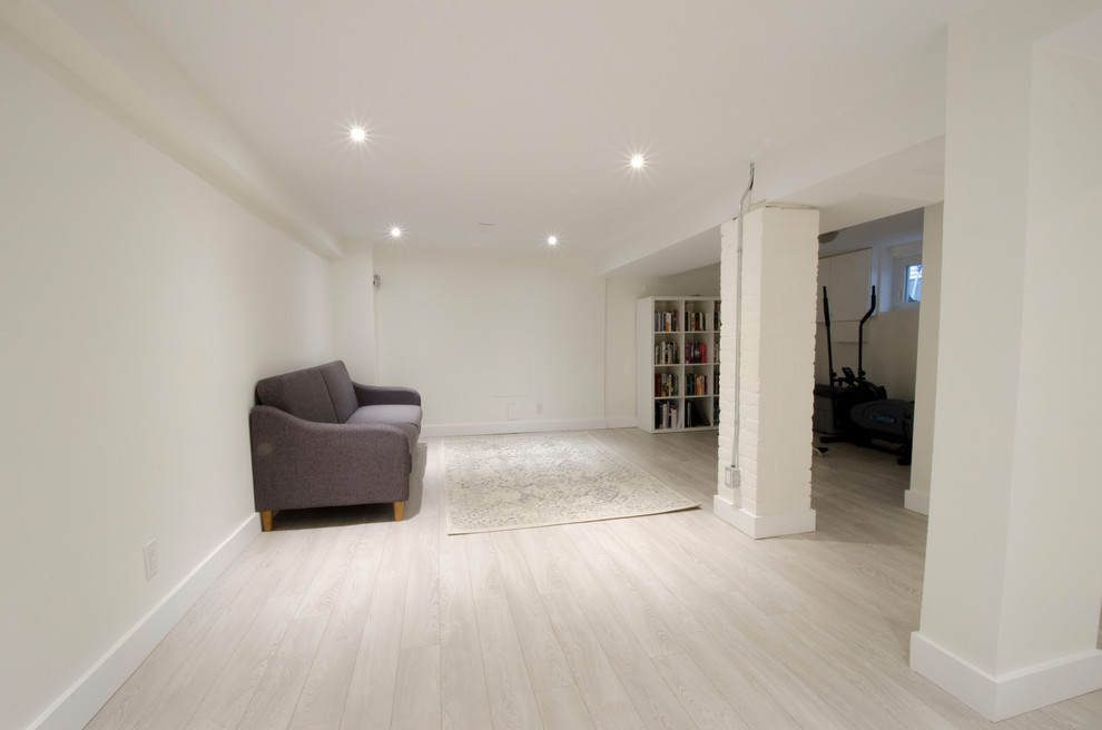 Example of a mid-sized transitional look-out laminate floor and beige floor basement design in Toronto with white walls