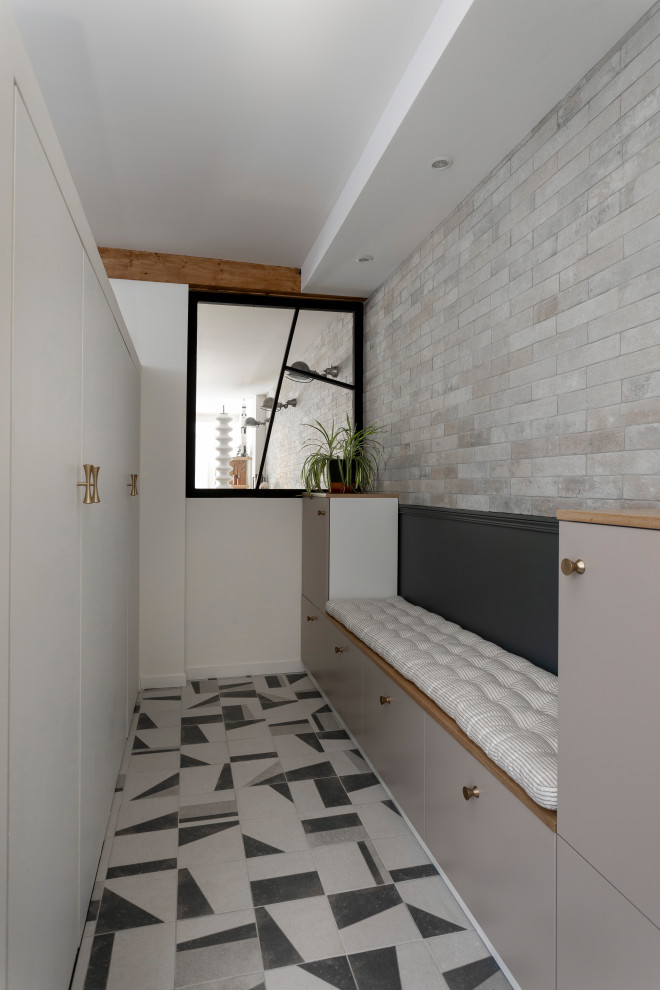 This is an example of a mid-sized industrial foyer in Paris with grey walls, terra-cotta floors, a single front door, a white front door, grey floor and brick walls.