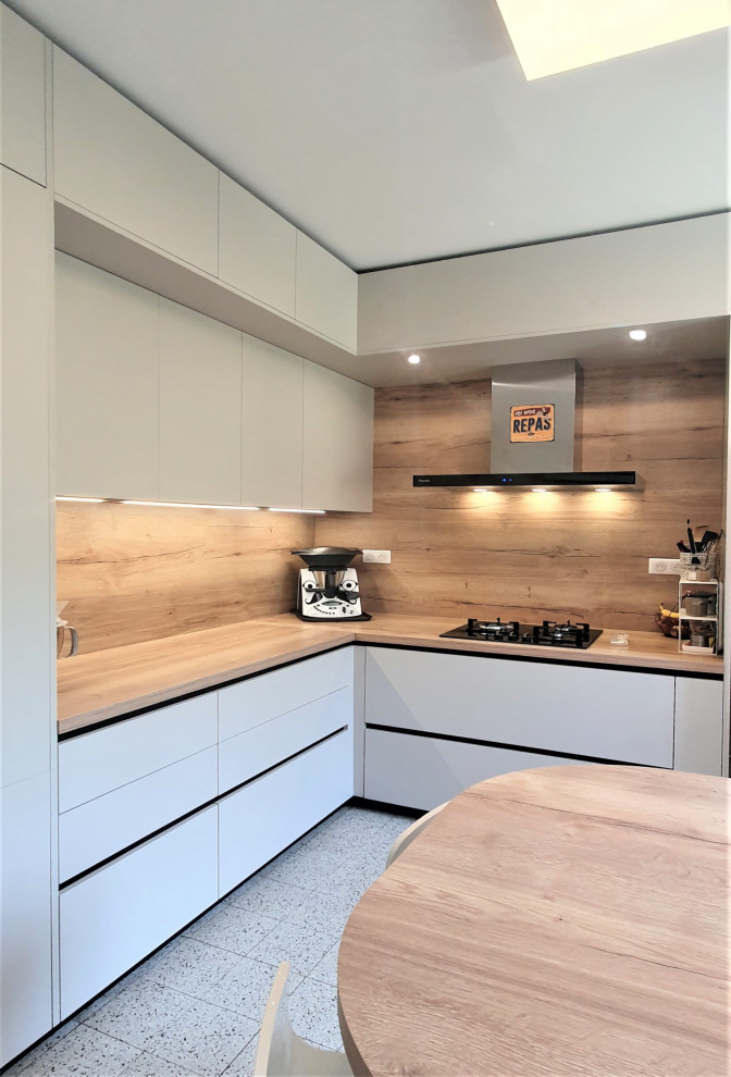 Inredning av ett modernt mellanstort brun brunt kök, med en undermonterad diskho, släta luckor, beige skåp, träbänkskiva, brunt stänkskydd, stänkskydd i trä, integrerade vitvaror, cementgolv, en köksö och grått golv