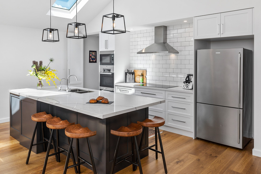 Inspiration for a large contemporary single-wall open plan kitchen in Sydney with an undermount sink, shaker cabinets, white cabinets, quartz benchtops, white splashback, porcelain splashback, stainless steel appliances, with island and white benchtop.