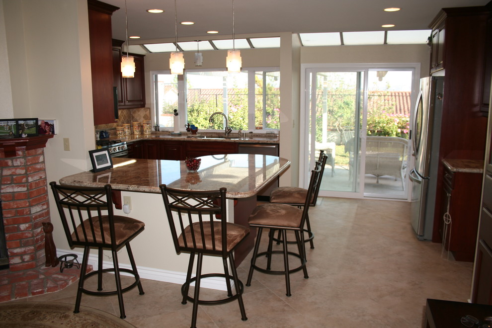 Inspiration for a large transitional u-shaped kitchen remodel in Orange County with raised-panel cabinets, dark wood cabinets and stainless steel appliances