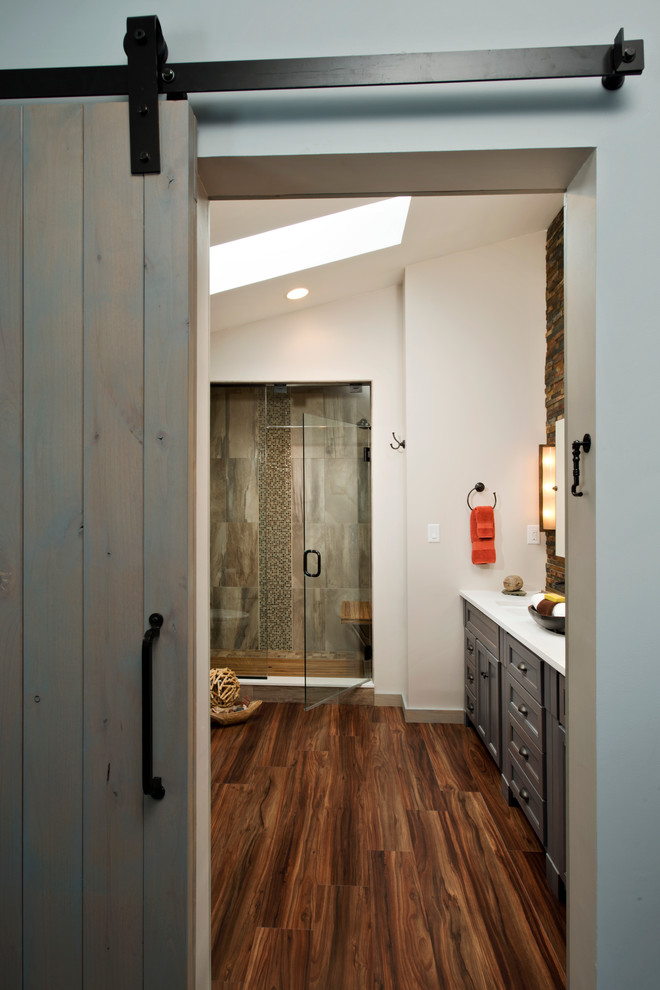 Design ideas for a mid-sized country master bathroom in Boston with recessed-panel cabinets, grey cabinets, a double shower, a two-piece toilet, gray tile, porcelain tile, beige walls, vinyl floors, an undermount sink and solid surface benchtops.