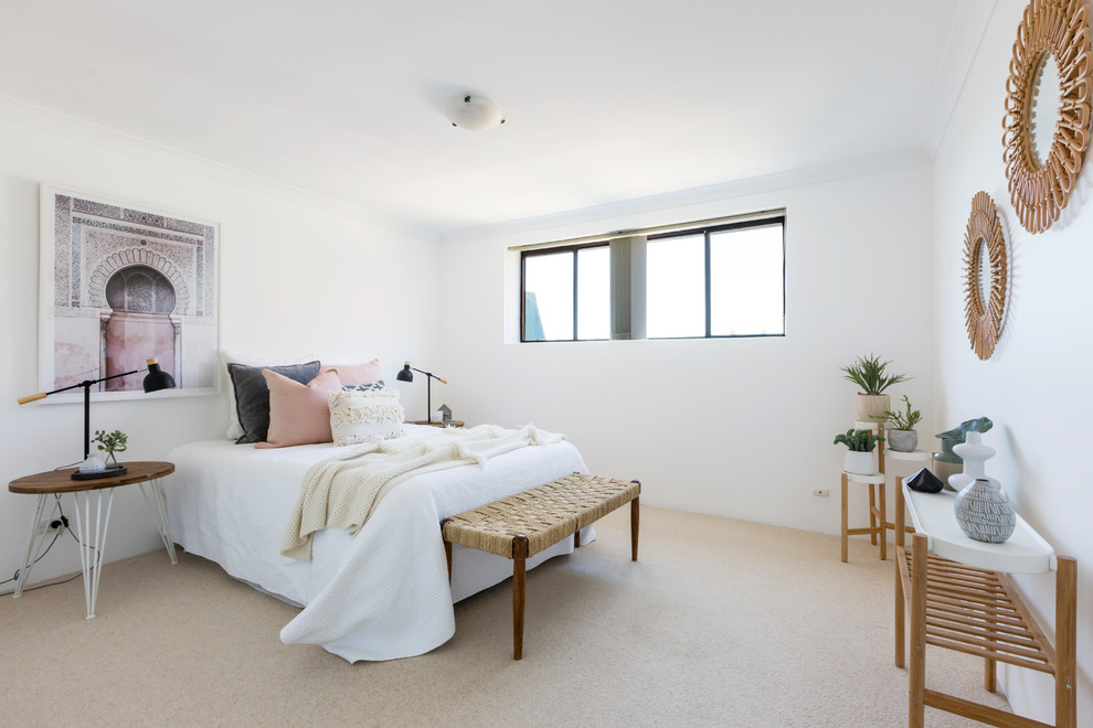 This is an example of a beach style bedroom in Sydney with white walls, carpet and beige floor.