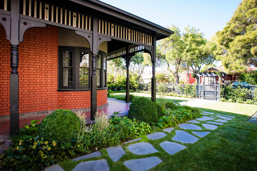 This is an example of a large contemporary front yard garden in Melbourne with natural stone pavers.