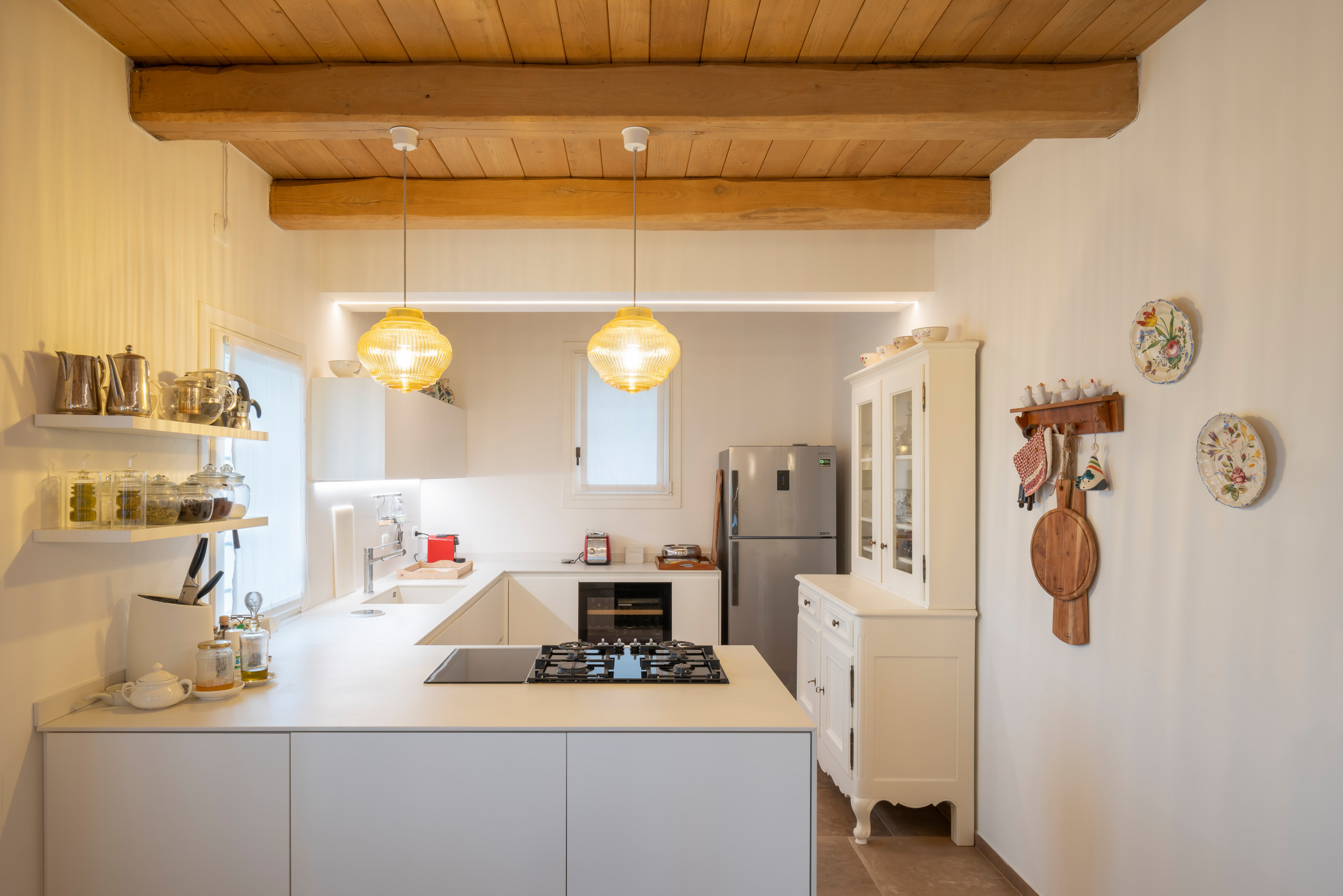 Example of a large farmhouse u-shaped porcelain tile, beige floor and wood ceiling open concept kitchen design in Other with a drop-in sink, flat-panel cabinets, white cabinets, solid surface countert