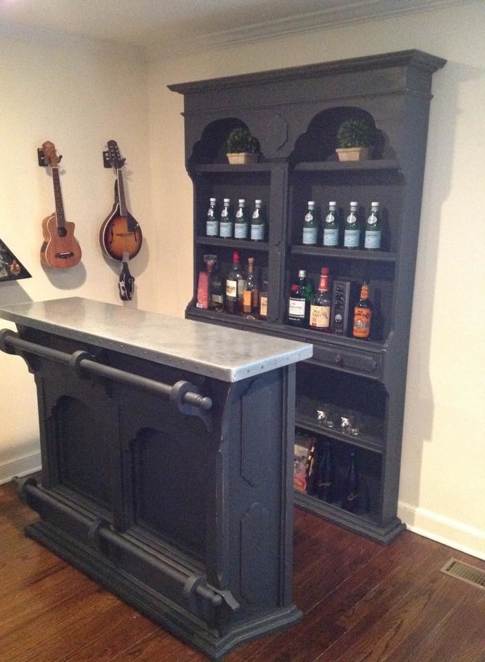 Photo of a mid-sized transitional single-wall seated home bar in New York with no sink, open cabinets, black cabinets, stainless steel benchtops and dark hardwood floors.