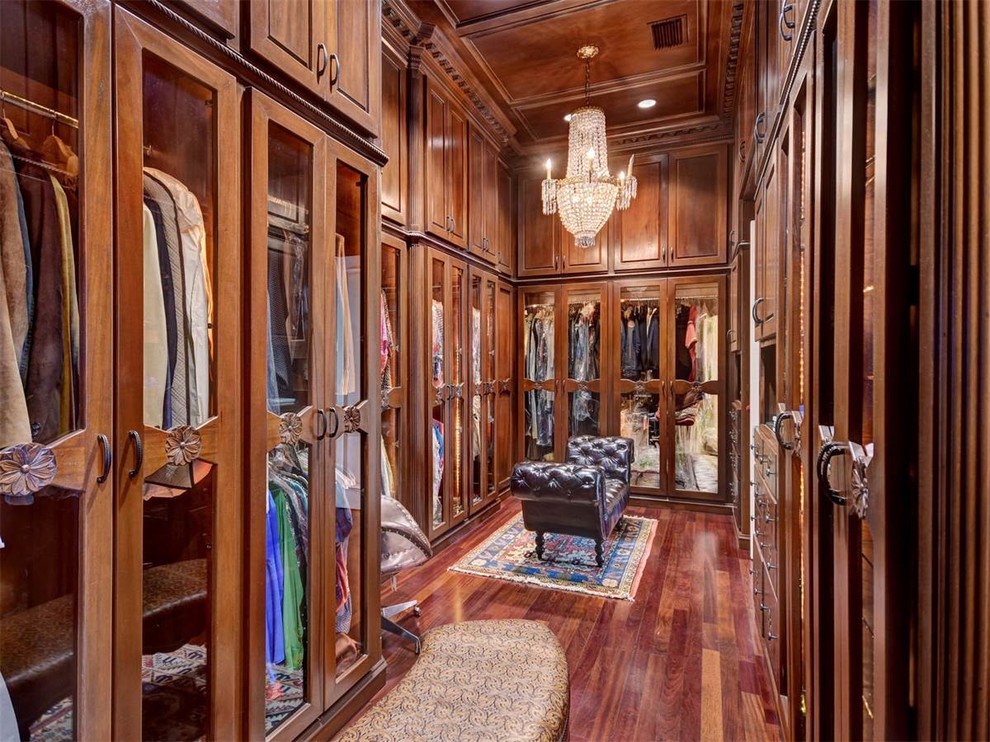 Large traditional gender-neutral walk-in wardrobe in Austin with glass-front cabinets, medium wood cabinets, medium hardwood floors and brown floor.