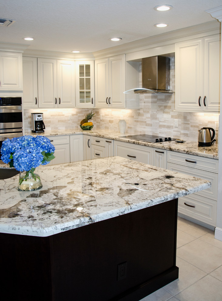 Mid-sized transitional l-shaped open plan kitchen in Miami with an undermount sink, raised-panel cabinets, white cabinets, granite benchtops, multi-coloured splashback, stone tile splashback, stainless steel appliances and with island.