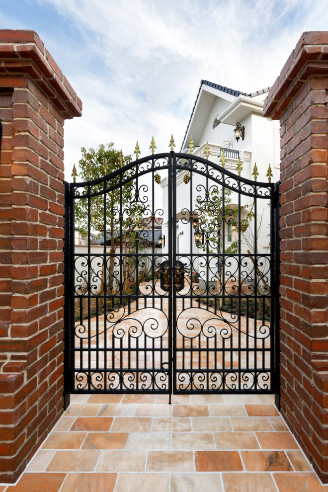 Immagine di un vialetto d'ingresso classico davanti casa con cancello, pavimentazioni in pietra naturale e recinzione in metallo