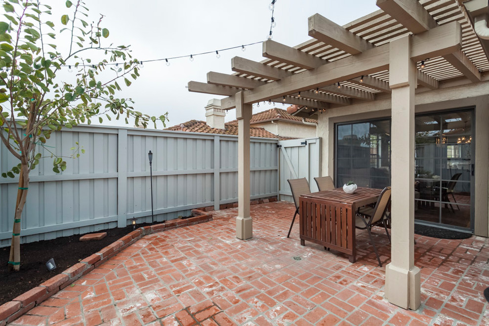 Small transitional courtyard patio in Los Angeles with brick pavers and a pergola.