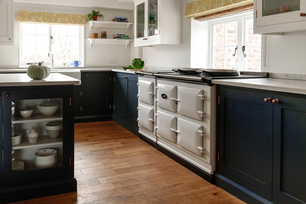 Photo of a mid-sized contemporary u-shaped eat-in kitchen in Sussex with a farmhouse sink, shaker cabinets, blue cabinets, quartzite benchtops, panelled appliances, medium hardwood floors, with island and brown floor.