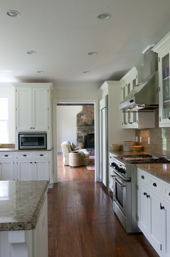 Country u-shaped eat-in kitchen in New York with a farmhouse sink, recessed-panel cabinets, white cabinets, granite benchtops, panelled appliances and medium hardwood floors.