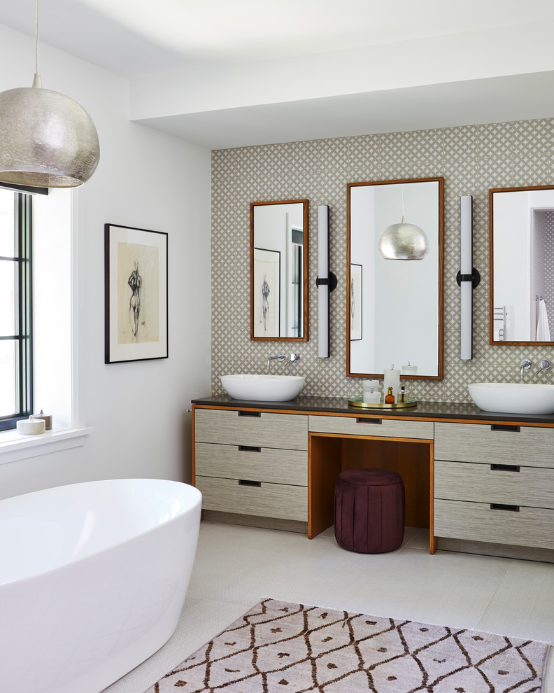 This is an example of a contemporary master bathroom in Toronto with a freestanding tub, multi-coloured walls, a vessel sink, beige floor, black benchtops and flat-panel cabinets.