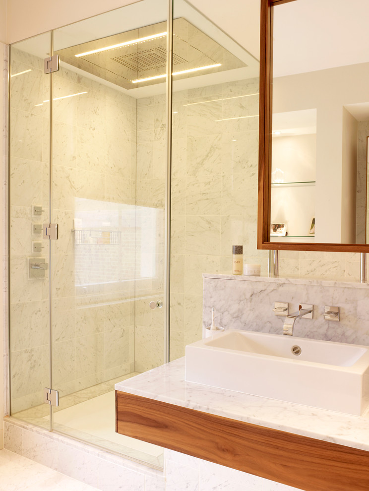 Mid-sized contemporary master bathroom in London with flat-panel cabinets, medium wood cabinets, an undermount tub, a corner shower, a wall-mount toilet, gray tile, marble, grey walls, marble floors, a console sink and marble benchtops.