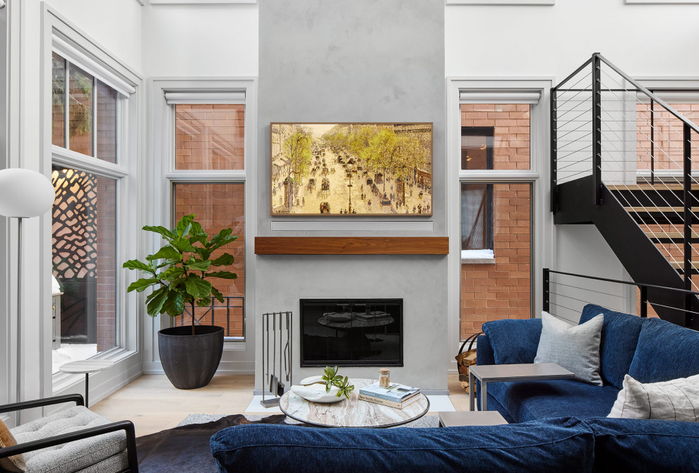 На фото: открытая гостиная комната в стиле модернизм с белыми стенами, светлым паркетным полом, стандартным камином, фасадом камина из бетона, скрытым телевизором и сводчатым потолком