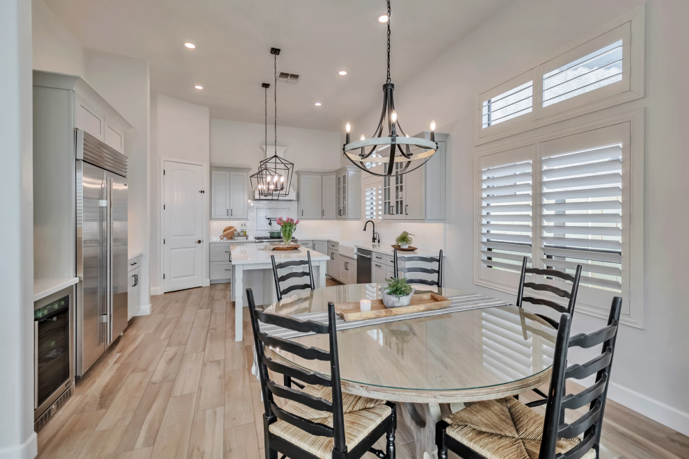 Inspiration for a large transitional u-shaped porcelain tile, brown floor and exposed beam kitchen remodel in Phoenix with a farmhouse sink, shaker cabinets, gray cabinets, quartzite countertops, white backsplash, porcelain backsplash, stainless steel appliances, an island and white countertops