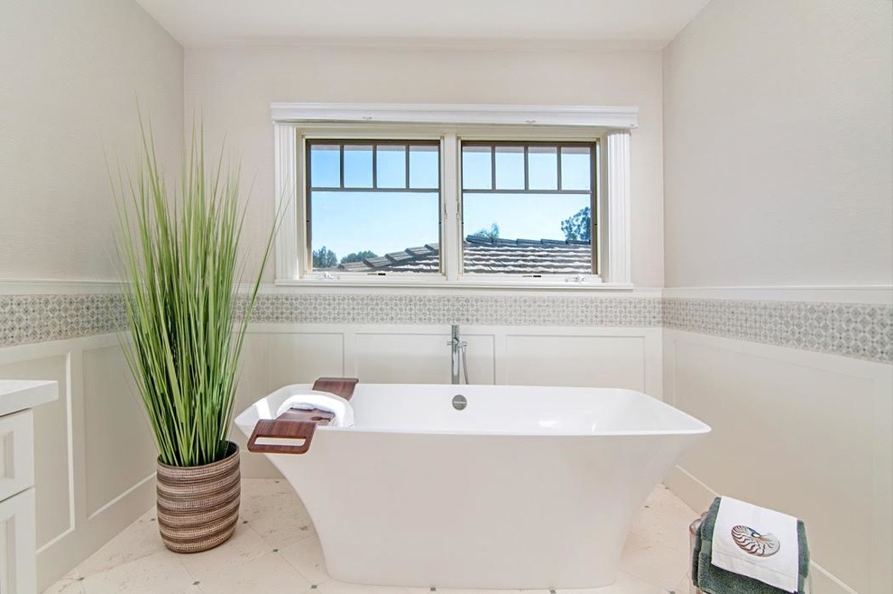 Large transitional master bathroom in San Diego with a freestanding tub, white walls, limestone floors, raised-panel cabinets, white cabinets, a double shower, white tile, stone tile, an undermount sink, engineered quartz benchtops, a one-piece toilet and white floor.