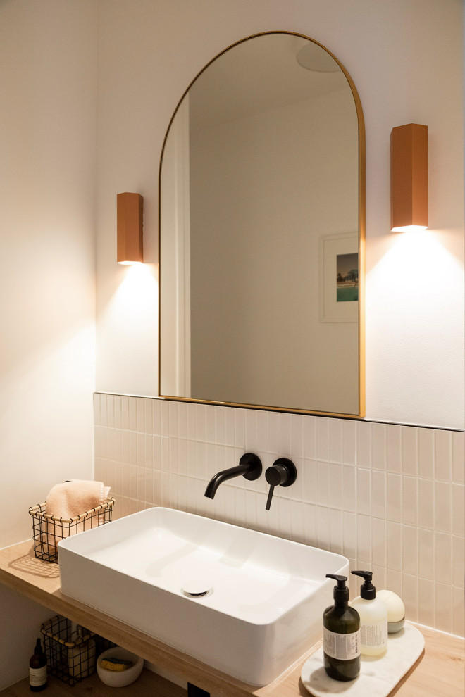 This is an example of a small cloakroom in Paris with open cabinets, light wood cabinets, a wall mounted toilet, white tiles, ceramic tiles, white walls, a vessel sink, wooden worktops, beige worktops and a floating vanity unit.