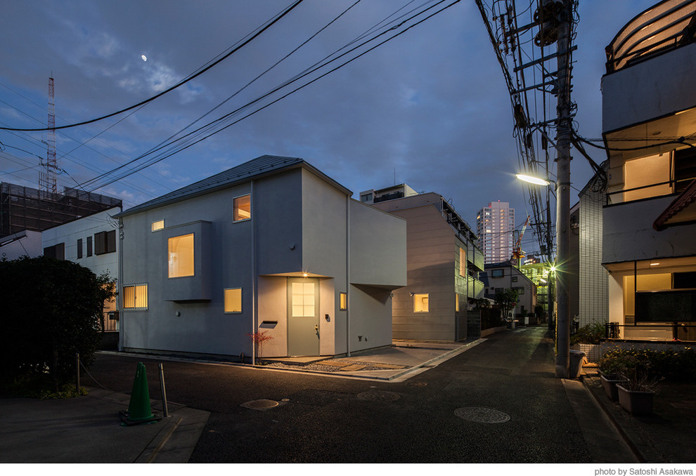 Photo of a mid-sized contemporary two-storey adobe grey exterior in Tokyo with a flat roof.