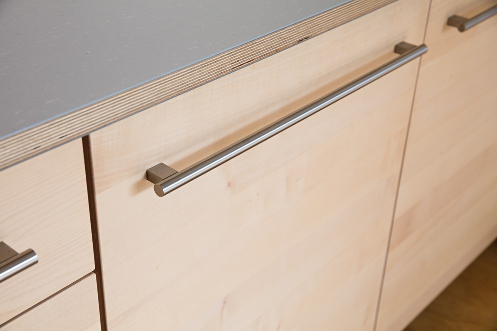 Küche in L-Form mit flächenbündigen Schrankfronten, hellen Holzschränken, Laminat-Arbeitsplatte, Küchenrückwand in Grau, Rückwand aus Holz und grauer Arbeitsplatte in Stuttgart