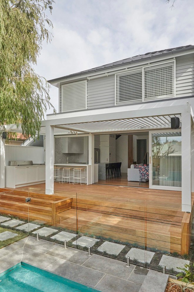 Photo of a mid-sized modern backyard deck in Sydney with an outdoor kitchen and an awning.