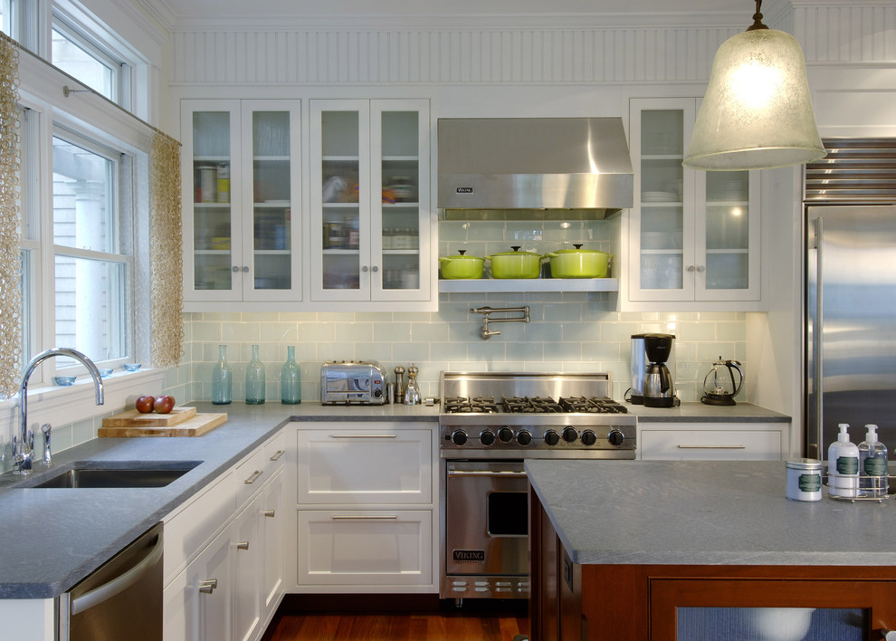 Transitional kitchen in Boston with glass-front cabinets, stainless steel appliances and subway tile splashback.