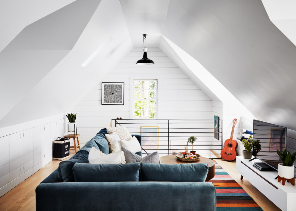 Inspiration for a mid-sized country loft-style family room in New York with white walls, medium hardwood floors, a freestanding tv and beige floor.