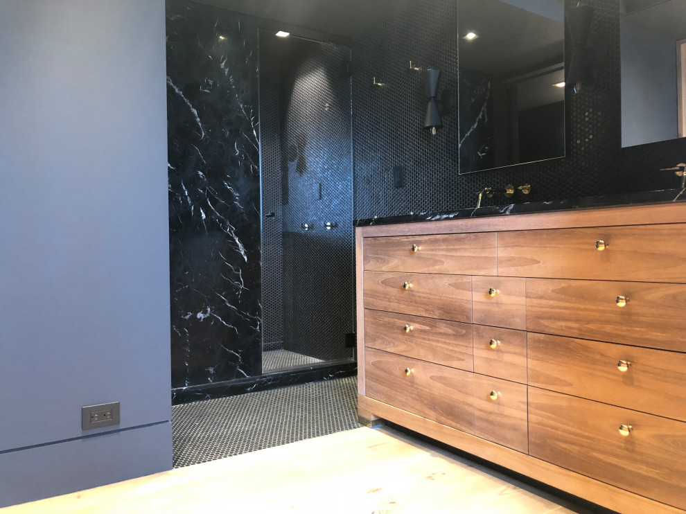 This is an example of a mid-sized contemporary master bathroom in New York with flat-panel cabinets, medium wood cabinets, an alcove shower, a two-piece toilet, black tile, marble, black walls, mosaic tile floors, an undermount sink, marble benchtops, black floor, an open shower and black benchtops.
