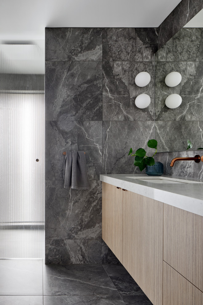 This is an example of a contemporary wet room bathroom in Melbourne with medium wood cabinets, a two-piece toilet, gray tile, porcelain tile, grey walls, terra-cotta floors, an undermount sink, engineered quartz benchtops, grey floor, a hinged shower door, white benchtops, a single vanity, a floating vanity and flat-panel cabinets.