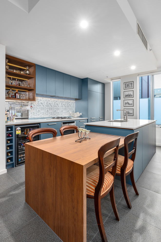 This is an example of a large modern galley eat-in kitchen in Melbourne with an undermount sink, flat-panel cabinets, blue cabinets, quartz benchtops, blue splashback, porcelain splashback, black appliances, porcelain floors, multiple islands, grey floor and white benchtop.