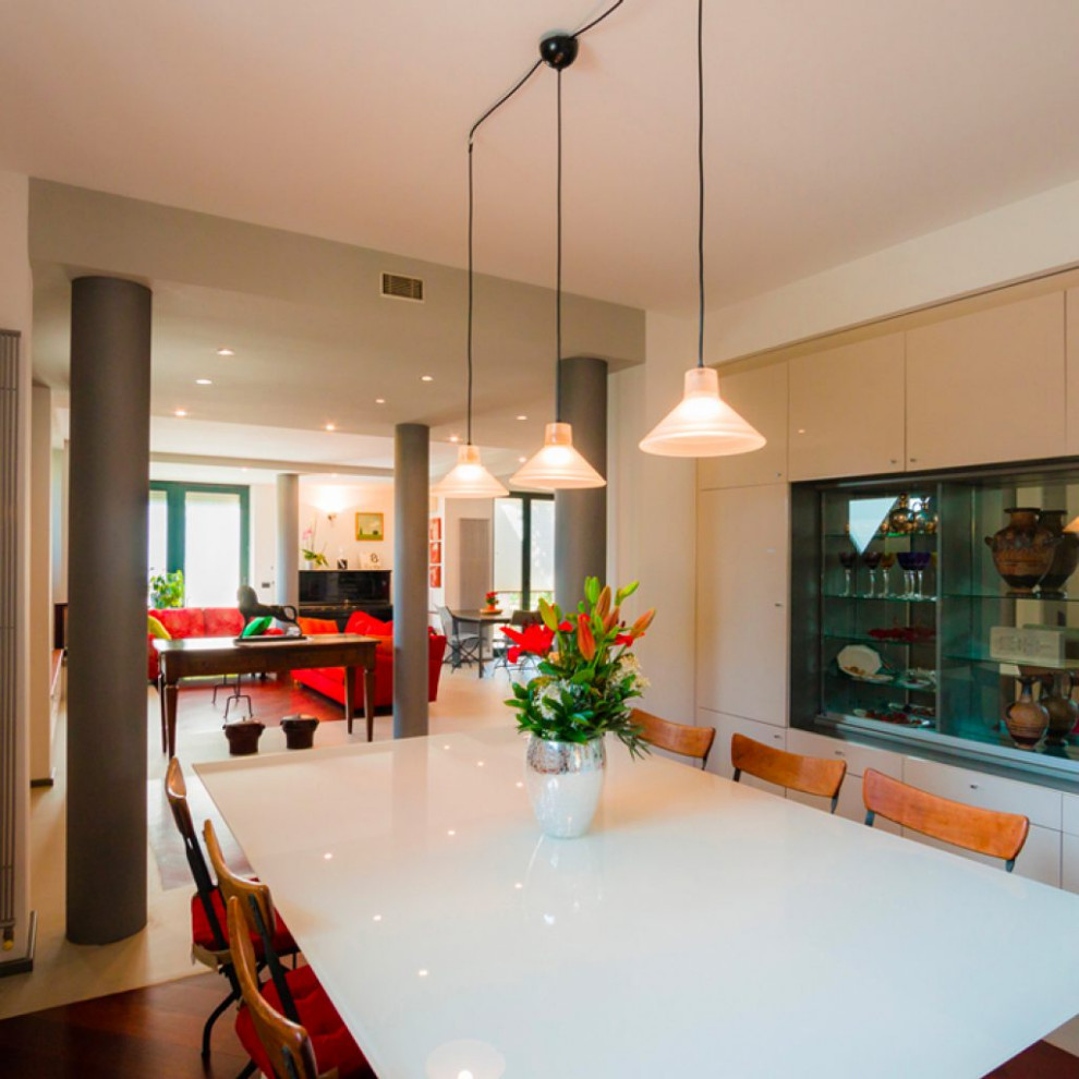 Photo of a separate dining room in Milan with white walls, dark hardwood floors and white floor.