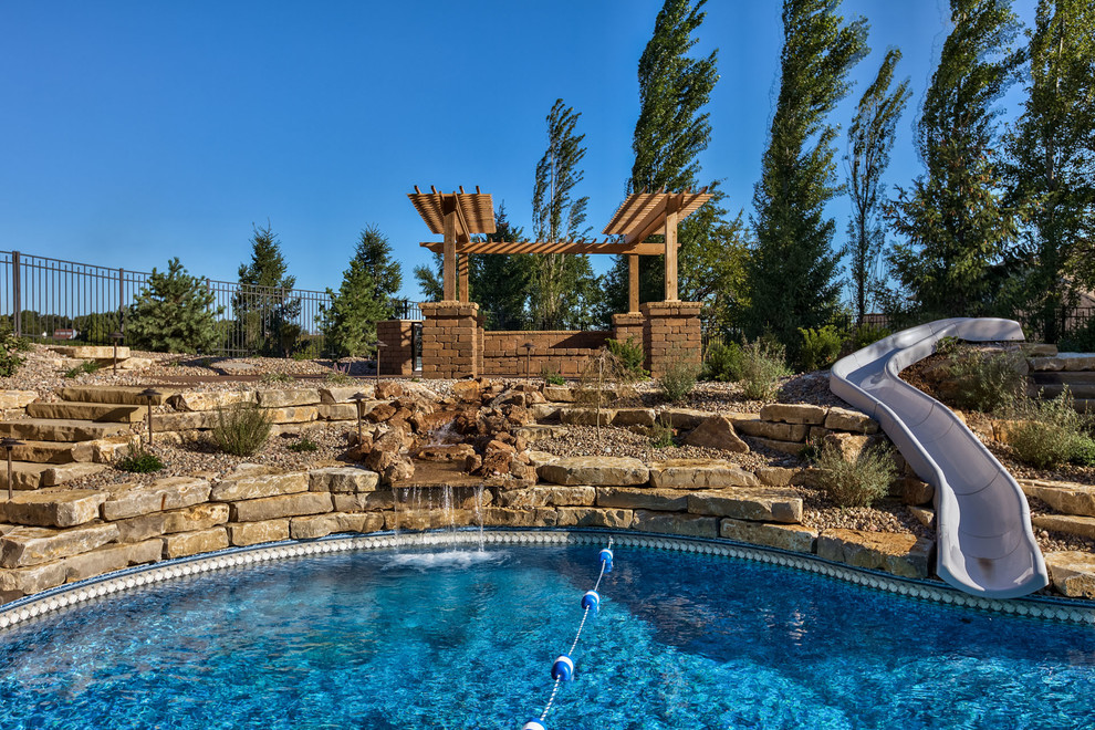 Pool fountain - large rustic backyard concrete paver and custom-shaped pool fountain idea in Omaha