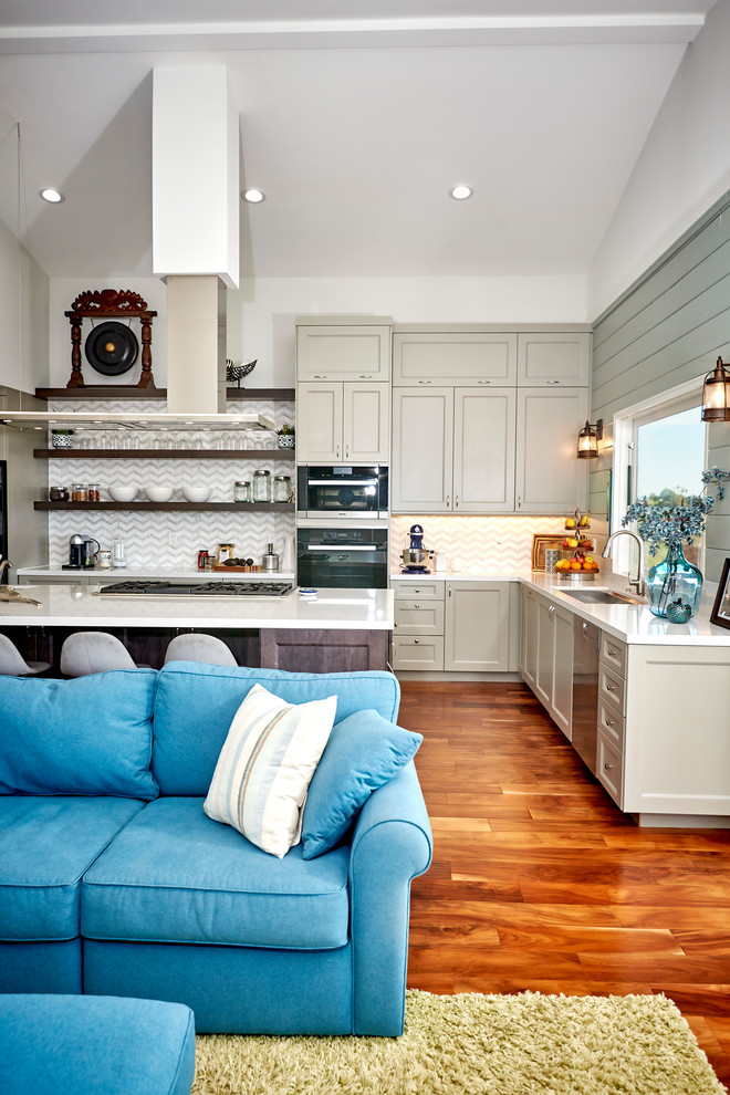 Example of a large transitional l-shaped medium tone wood floor and brown floor open concept kitchen design in Denver with an undermount sink, recessed-panel cabinets, gray cabinets, quartz countertops, white backsplash, marble backsplash, stainless steel appliances, an island and white countertops