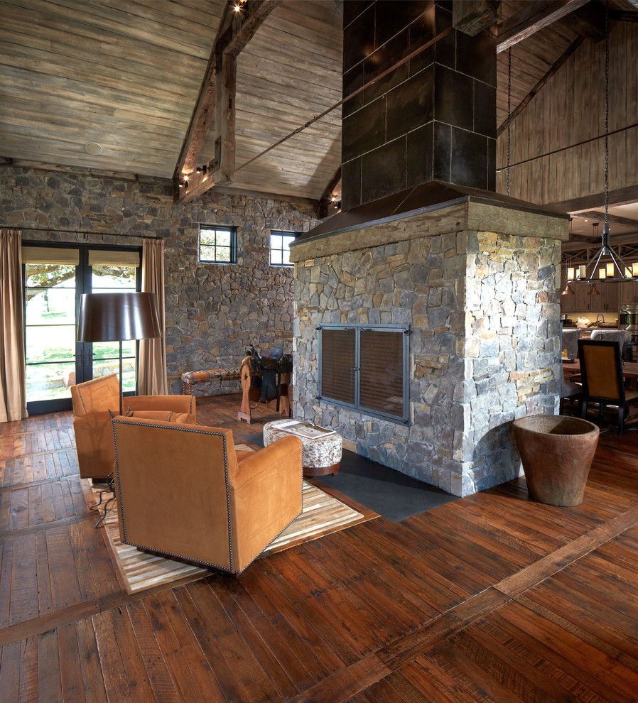 This is an example of a country open concept family room in Houston with dark hardwood floors, a standard fireplace and a stone fireplace surround.