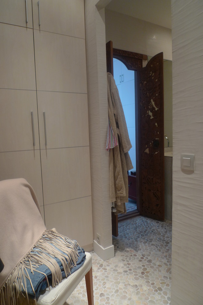 Mid-sized transitional gender-neutral dressing room in Paris with beaded inset cabinets, beige cabinets and beige floor.