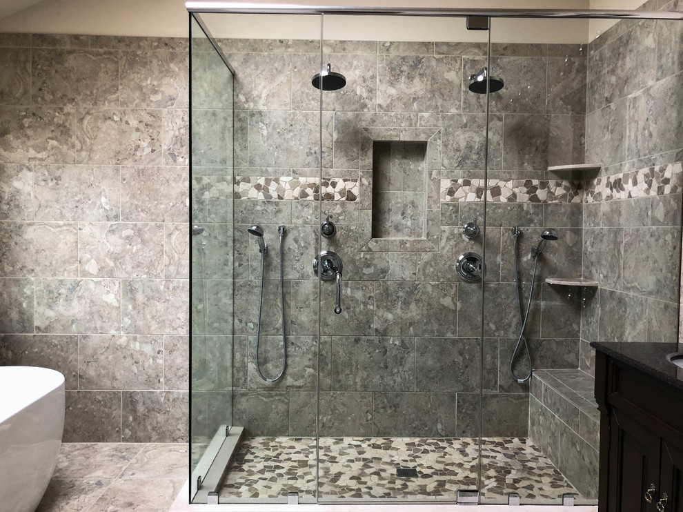 Photo of a large transitional master bathroom in Philadelphia with raised-panel cabinets, dark wood cabinets, a freestanding tub, a corner shower, a two-piece toilet, gray tile, ceramic tile, beige walls, travertine floors, an undermount sink, granite benchtops and black benchtops.