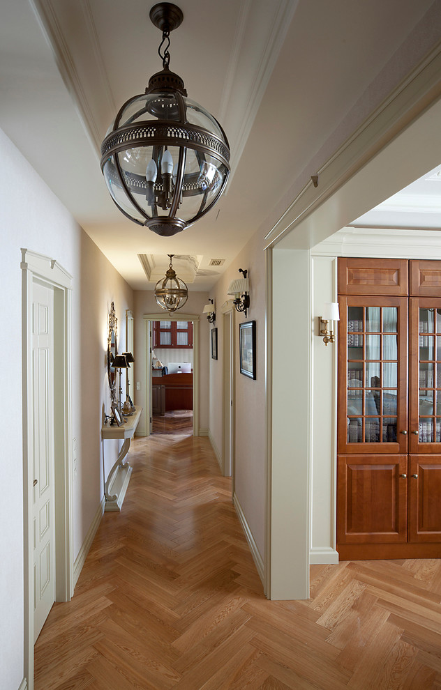 This is an example of a traditional hallway in Moscow with beige walls and medium hardwood floors.