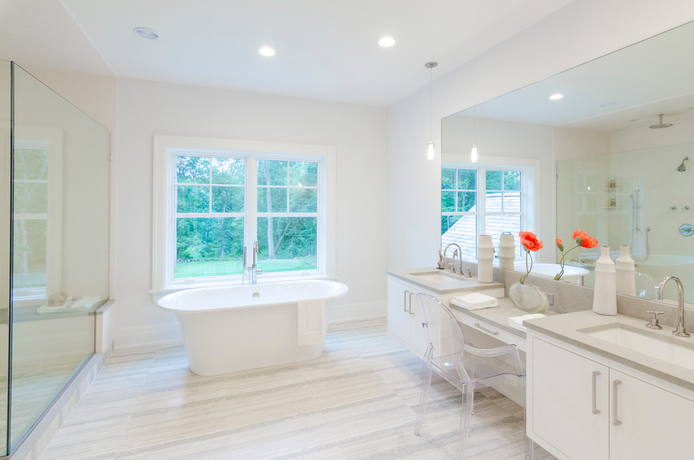 Photo of a large transitional master bathroom in New York with flat-panel cabinets, white cabinets, an alcove shower, beige tile, white walls, a drop-in sink, engineered quartz benchtops, a freestanding tub, stone slab and porcelain floors.