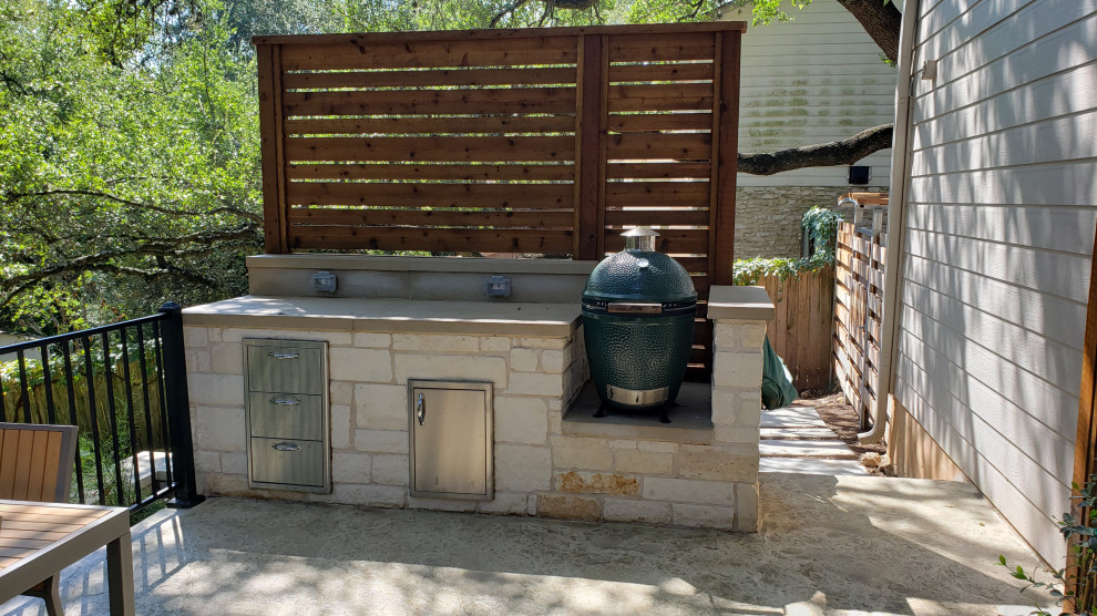 Photo of a large eclectic backyard patio in Austin with an outdoor kitchen, concrete slab and a roof extension.