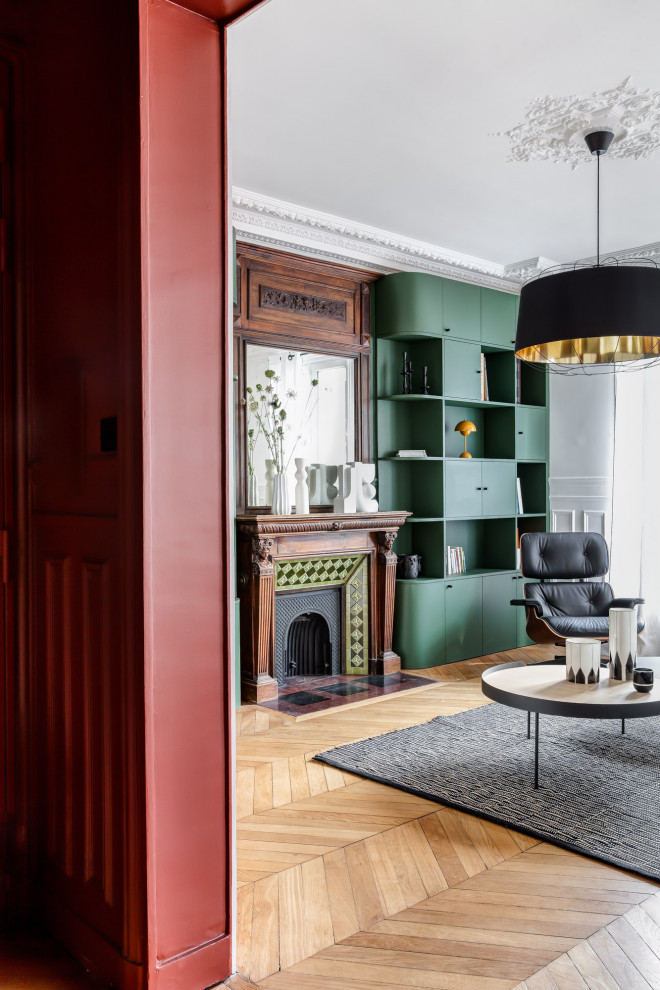 Пример оригинального дизайна: открытая гостиная комната среднего размера в современном стиле с с книжными шкафами и полками, зелеными стенами, светлым паркетным полом, стандартным камином, фасадом камина из дерева, мультимедийным центром и панелями на стенах