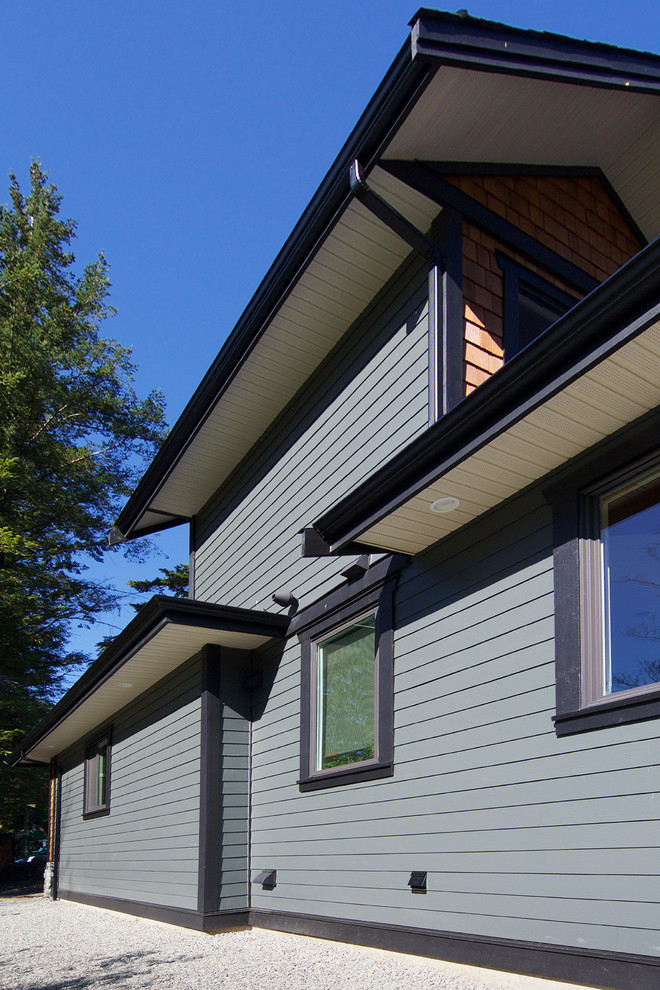Example of a mountain style brown two-story concrete fiberboard exterior home design in Vancouver with a clipped gable roof