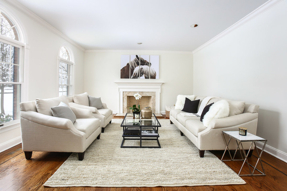 This is an example of a mid-sized transitional formal enclosed living room in New York with white walls, a stone fireplace surround, medium hardwood floors, a standard fireplace, no tv and brown floor.