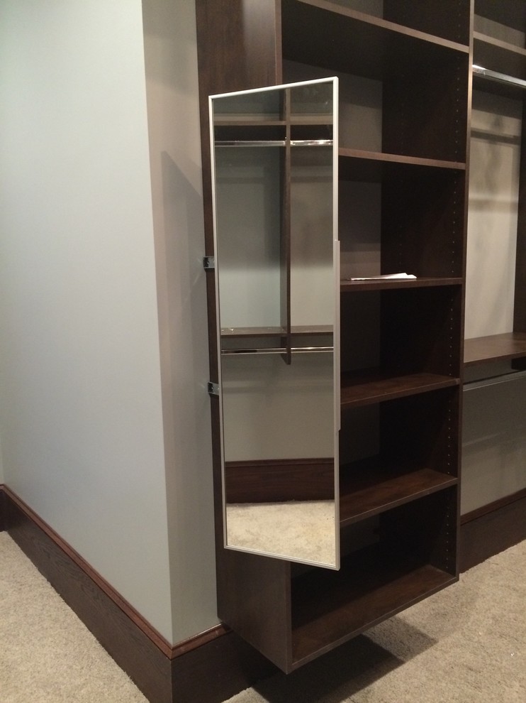 This is an example of a large contemporary women's walk-in wardrobe in Indianapolis with brown cabinets and carpet.
