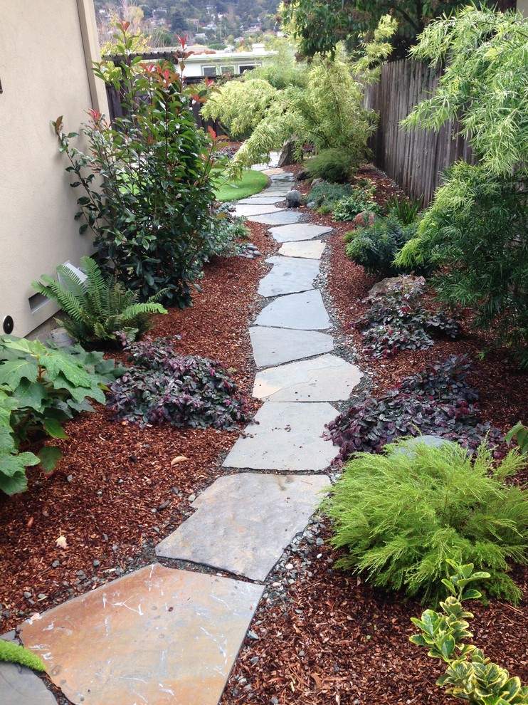 This is an example of an eclectic backyard formal garden in San Francisco with natural stone pavers.
