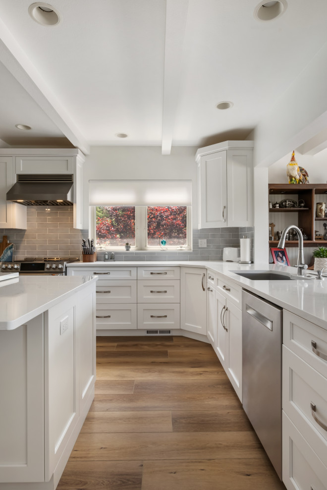 Inspiration for a mid-sized beach style galley eat-in kitchen in Seattle with a drop-in sink, beaded inset cabinets, white cabinets, marble benchtops, grey splashback, ceramic splashback, stainless steel appliances, vinyl floors, multiple islands, brown floor, white benchtop and coffered.