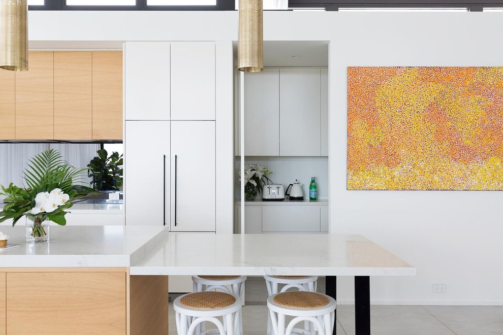 This is an example of a contemporary kitchen pantry in Sydney with a drop-in sink, light wood cabinets, black appliances, cement tiles, multiple islands, grey floor, flat-panel cabinets, marble benchtops, mirror splashback and multi-coloured benchtop.