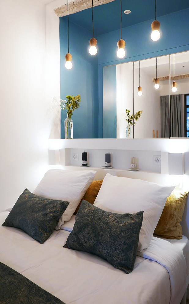 Imagen de dormitorio principal actual de tamaño medio con paredes azules, suelo laminado y vigas vistas