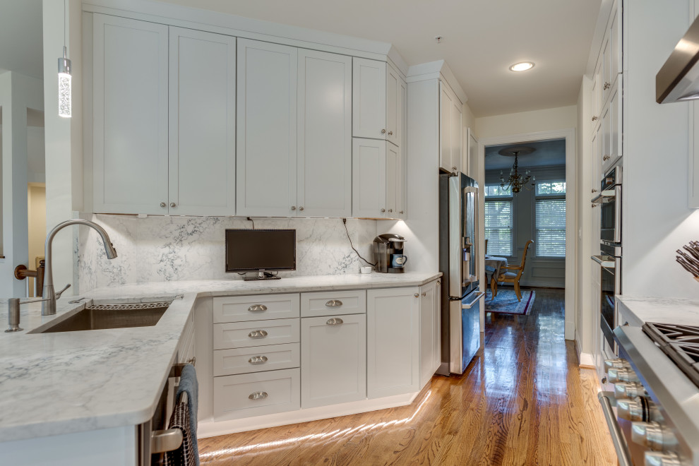 Foto på ett litet funkis u-kök, med en undermonterad diskho, luckor med infälld panel, vita skåp, bänkskiva i kvartsit, rostfria vitvaror och en halv köksö