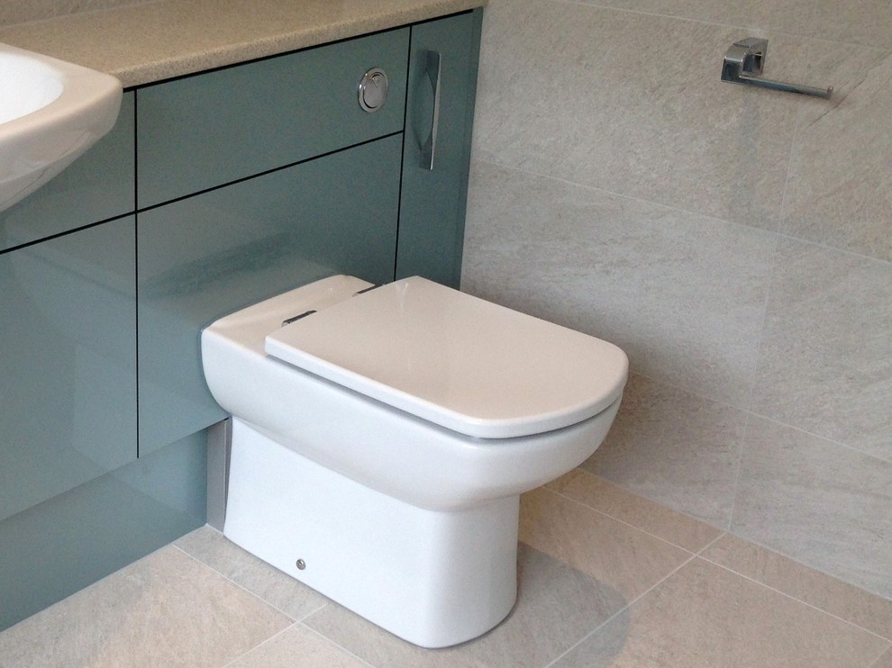 This is an example of a mid-sized contemporary kids bathroom in Berkshire with flat-panel cabinets, laminate benchtops, an open shower, a one-piece toilet, gray tile, porcelain tile, grey walls and porcelain floors.